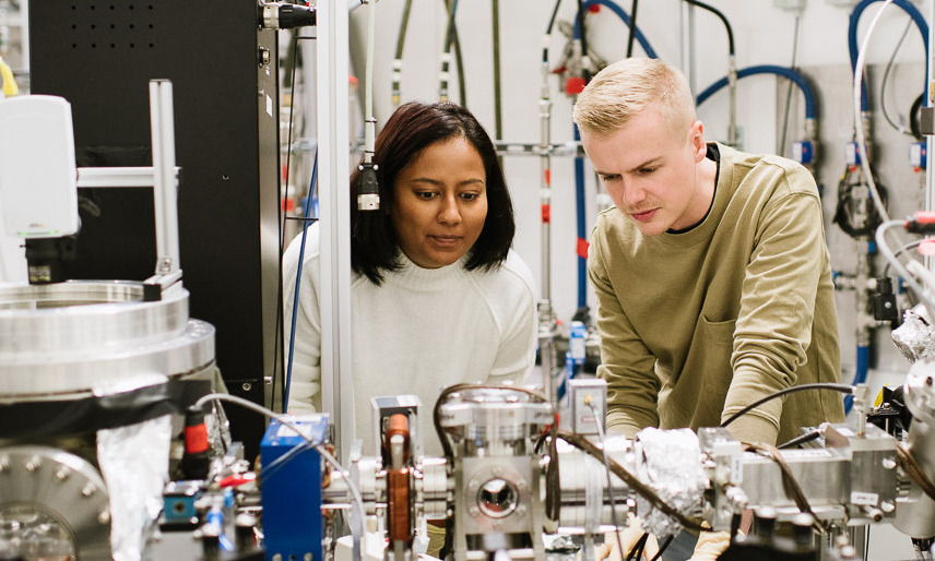 Zwei Forschende untersuchen komplexe Laborausrüstung in einem wissenschaftlichen Labor.